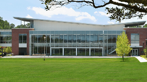 contemporary metal and glass environmental science center on a college campus with green lawns and trees