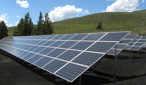 array of solar panels outside with green grass and blue sky in background